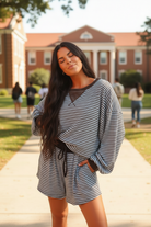 Dark brunette model wearing brown stripe oversized long sleeve top and matching drawstring shorts - three-quarter playful pose outdoors on college campus