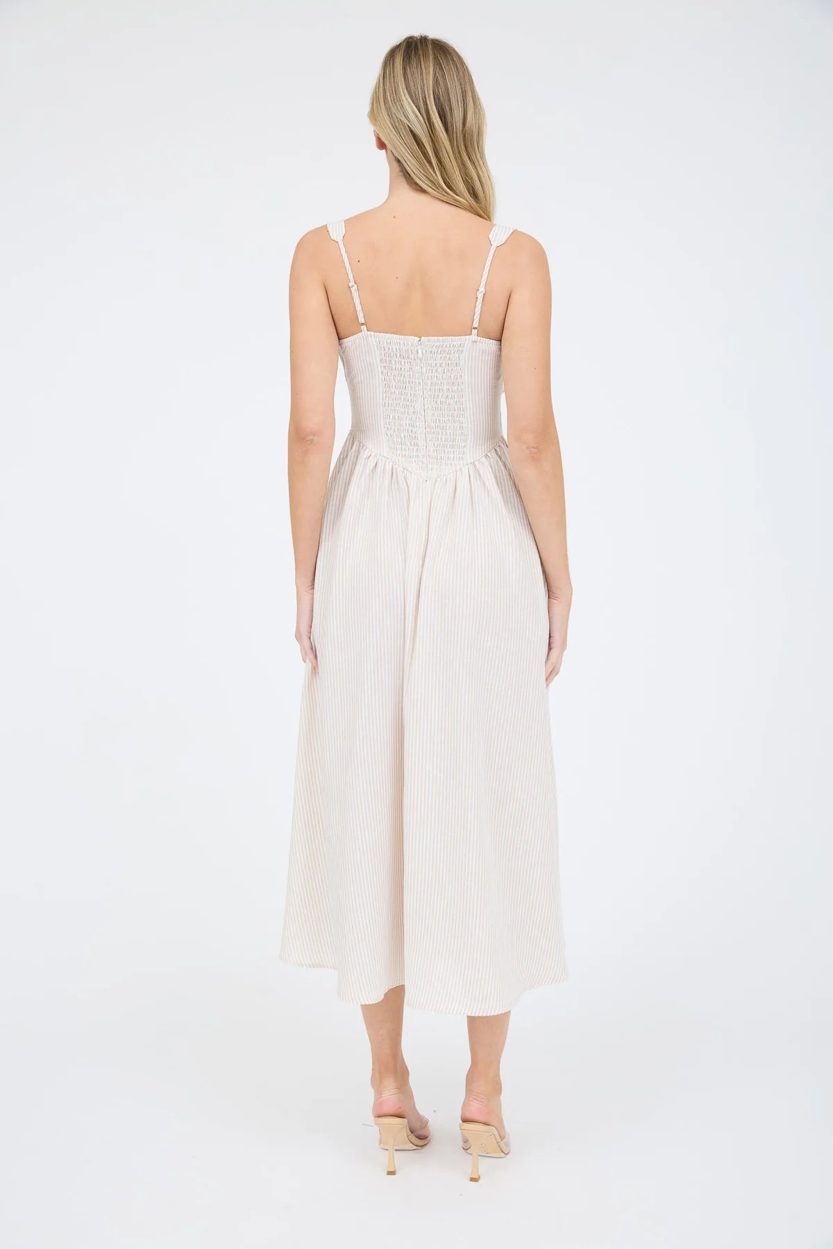 Rear view of a striped midi dress showcasing a functional smocked back dress panel for an adjustable fit. The taupe stripes remain continuous from the shoulder straps down to the hem of the A-line summer dress taupe and white