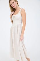 A coastal chic fashion staple, this sleeveless striped dress is made from a lightweight, breathable fabric. The image captures the crisp texture of the taupe stripes and the structured yet airy drape of the A-line summer dress silhouette front view
