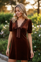 Close-up of brown velvet mini dress lace V-neckline and velvet bow tie front detail, outdoor fashion editorial