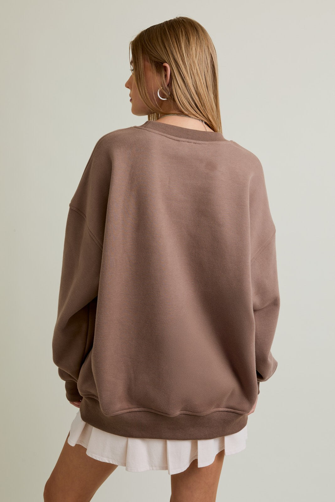 Woman wearing a mocha oversized crewneck sweatshirt with “Western” embroidery and a cowboy graphic