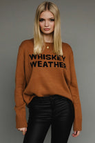 Camel knit sweater with “Whiskey Weather” black lettering, relaxed cozy fit.