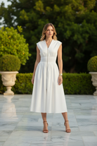 Brunette model wearing white zip front smocked waist midi dress with full A-line skirt, front-facing full body shot on marble terrace with lush greenery, elevated boutique lifestyle photo