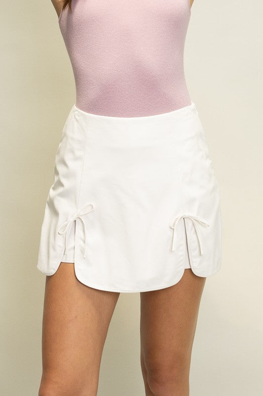 Butter soft faux leather tulip skort with bow tie detail and built-in shorts for women from Thread Bar Boutique